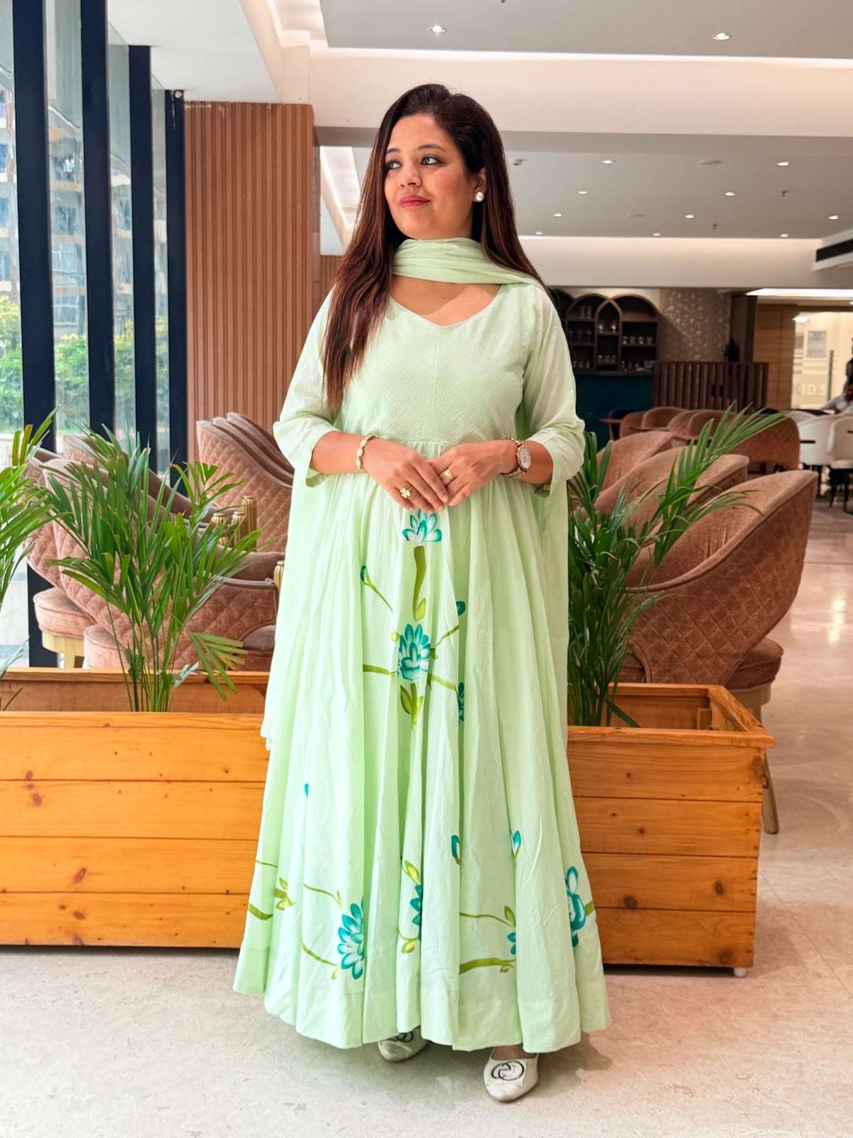 a mint green mul cotton hand-painted anarkali suit with a flowy silhouette and vibrant blue floral detailing along the hem and bodice