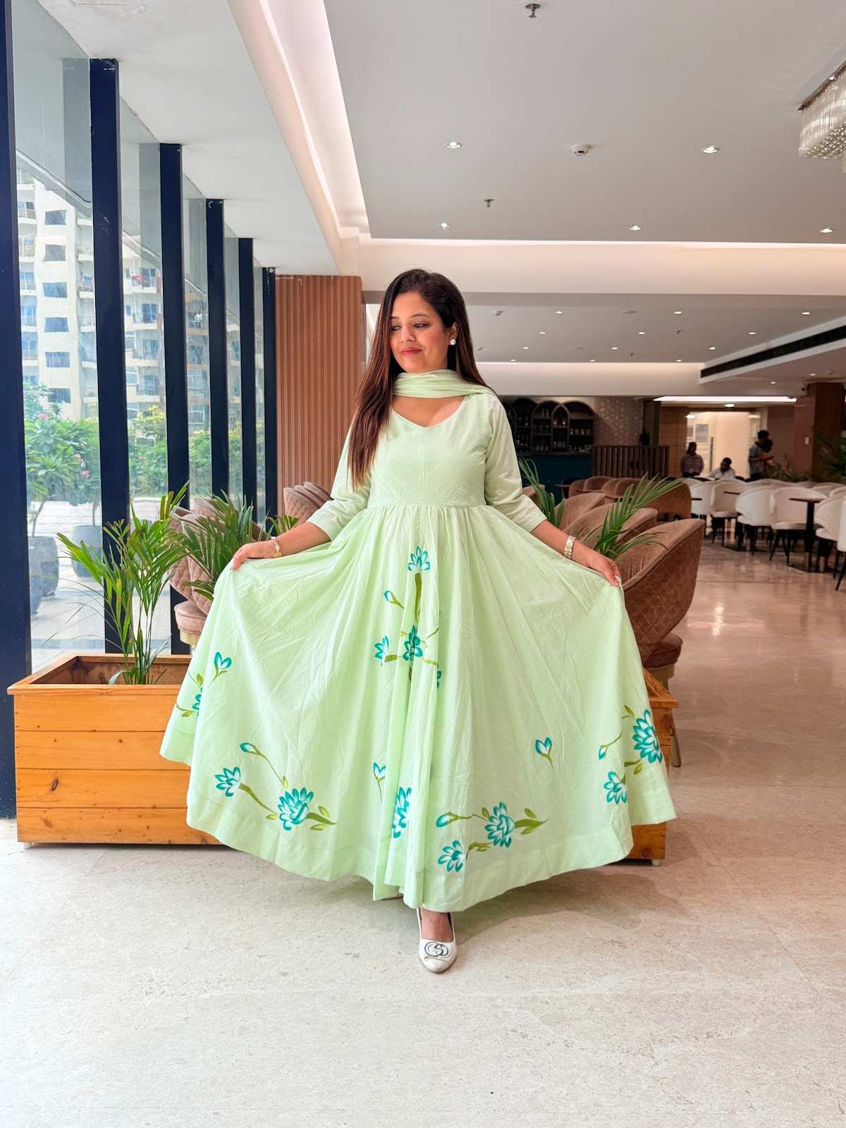 a mint green mul cotton hand-painted anarkali suit with a flowy silhouette and vibrant blue floral detailing along the hem and bodice