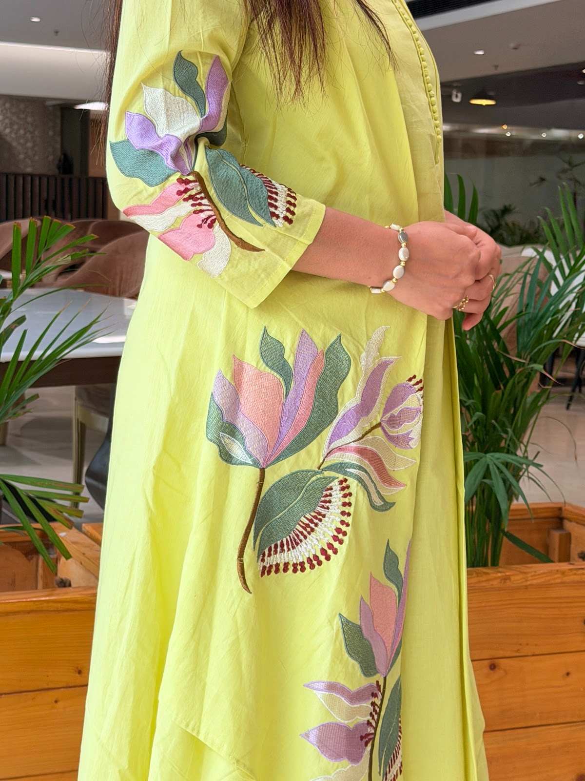 cotton lime green kurta set featuring an elegant, asymmetrical layered design with delicate floral embroidery on the front panel and sleeves, complete with a button-detail neckline