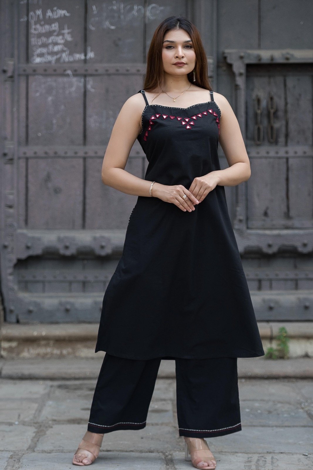 Strapy black sleeveless A-line kurta and matching palazzo pants featuring geometric red embroidery and mirror work along the neckline
