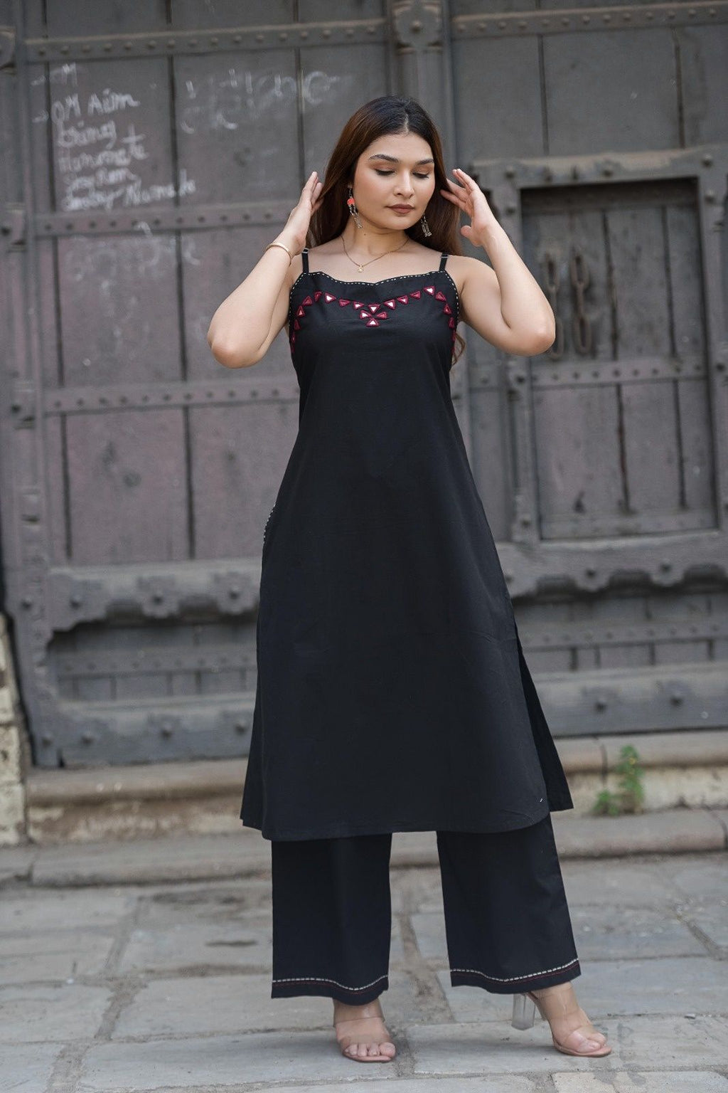 Strapy black sleeveless A-line kurta and matching palazzo pants featuring geometric red embroidery and mirror work along the neckline