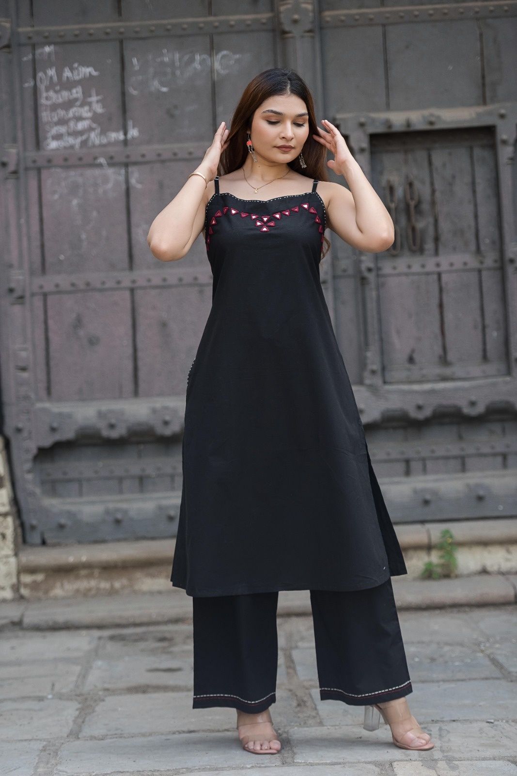 Strapy black sleeveless A-line kurta and matching palazzo pants featuring geometric red embroidery and mirror work along the neckline